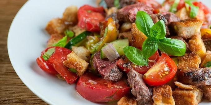 receta de ensalada con carne, pan frito, tomates cherry y albahaca