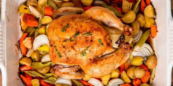 Un pollo entero en el horno sobre una cama de verduras
